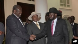 Riek Machar, ancien vice-président du Soudan du Sud, salue le président sud-soudanais Salva Kiir, a droite, sous le regard du président ougandais Yoweri Museveni lors d’une réunion de sécurité à Entebe, Ouganda, 7 juillet 2018.