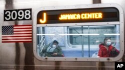 纽约地铁车厢里带着口罩和手套的乘客。