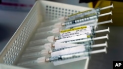 Syringes containing the Pfizer-BioNTech COVID-19 vaccine sit in a tray in a vaccination room at St. Joseph Hospital in Orange, Calif., on Jan. 7, 2011. Taking a new direction to speed re