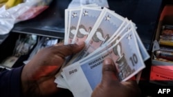 A cashier in a leading supermarket dispenses the new $10 ZiG, short for Zimbabwe Gold, note from a till as change in Harare on April 30, 2024.