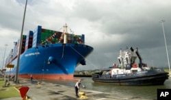In this Dec. 3, 2018, photo, a Panama Canal worker docks the Chinese container ship Cosco at the Panama Canals' Cocoli Locks, in Panama City. (AP Photo/Arnulfo Franco)