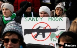 People hold signs memorializing Sandy Hook Elementary School, where 26 children and adults were killed in a mass shooting in December, as they participate in the March on Washington for Gun Control on the National Mall in Washington, January 26, 2013.