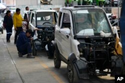 An employee works on a Quantum electric car on an assembly line at a factory in Cochabamba, Bolivia on May 9, 2023. (AP Photo/Juan Karita)
