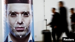People walk past a poster simulating facial recognition software at the Security China 2018 exhibition on public safety and security in Beijing, China October 24, 2018. (REUTERS/Thomas Peter)