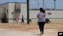 In this Aug. 23, 2019 file photo, immigrants seeking asylum walk at the ICE South Texas Family Residential Center, in Dilley, Texas. (AP Photo/Eric Gay, File) 