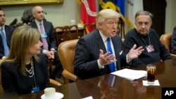 President Donald Trump, flanked by GM CEO Mary Barra and Fiat Chrysler Automobiles CEO Sergio Marchionne, gestures while speaking at the start of a meeting with automobile leaders in the Roosevelt Room of the White House in Washington, Jan. 24, 2017. 
