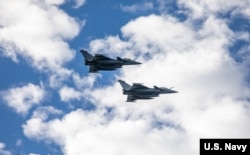 资料照片：2022年11月16日，两架法国“阵风”战斗机飞过美国海军“罗斯福号”导弹驱逐舰。(美国海军照片)