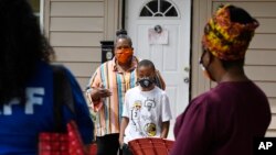 n this Friday, June 5, 2020 photo, Titilaya Thompson and her son Nehemiah talk with Dr. Tayarisha Batchelor, right, and Community School Director for The Village for Families and Children Trisila Tirado, left, in Hartford, Conn. (AP Photo/Jessica Hill)