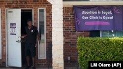 FILE - In this Sept. 1, 2021 file photo, a security guard opens the door to the Whole Women's Health Clinic in Fort Worth, Texas.