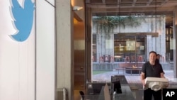 马斯克搬着一个洗手池盆进入在旧金山的推特总部。（2022年10月26日）