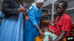 FILE - A health worker prepares to vaccinate a child against malaria, at Mitundu Community Hospital, in Malawi's capital of Lilongwe, April 23, 2019.