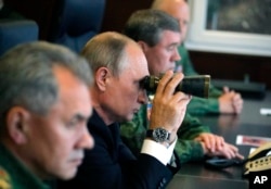 FILE - Russian President Vladimir Putin, center, Defense Minister Sergei Shoigu, left, and Chief of the General Staff of the Russian Armed Forces Valery Gerasimov, right, watch a military exercise at a training ground at the Luzhsky Range, near St. Petersburg.
