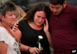 Glorymar Valley, center, is comforted by Christian Caballero, right, and Natividad Rivera, as they mourn the loss of their friend Javier Jorge-Reyes