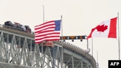 နှစ်နိုင်ငံနယ်စပ် အမေရိကန်ဘက်ခြမ်း St. Clair မြစ်အနီး Bluewater တံတားပေါ်တွင် လွှင့်ထူထားသည့် အမေရိကန်နှင့် ကနေဒါအလံများ။ (ဇန်နဝါရီ ၂၉၊ ၂၀၂၅)