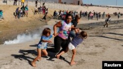 A migrant family, part of a caravan of thousands traveling from Central America en route to the United States, run away from tear gas in front of the border wall between the U.S and Mexico in Tijuana, Mexico November 25, 2018. REUTERS/Kim Kyung-Hoon 