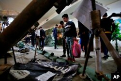 In this Friday, Feb. 1, 2019 photo, a flag of the Islamic State group and some of the weapons they used in battle, are on display in the Popular Mobilization Forces War Museum on al-Mutanabi Street, Baghdad, Iraq. (AP Photo/Khalid Mohammed)