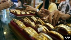 Picture taken on September 1, 2010 shows Myanmar vendors arranging a display of gold jewellery at a jewellery shop at Chinatown in downtown Yangon. Housewives huddle over jewellery counters in Yangon's bustling Chinatown -- but they do not have fashion o