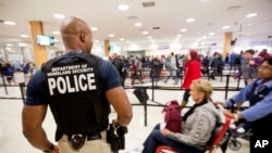 In this file photo, a Department of Homeland Security police officer stands at a security checkpoint at Hartsfield–Jackson Atlanta International Airport, Nov. 25, 2015.