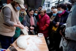 People wearing protective masks wait to buy food at a street market almost a year after the start of the coronavirus disease (COVID-19) outbreak, in Wuhan, Hubei province, China December 7, 2020. Picture taken December 7, 2020. REUTERS/Aly Song