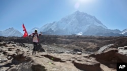 FILE - A Nepalese runs with his national flag during a marathon to mark the first conquest of Mount Everest, at Lobuche, near Everest base camp, Nepal, Monday, May 29, 2017. (AP Photo/Tashi Sherpa)