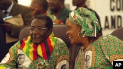 President Robert left listens to his wife Grace at a Zanu PF Conference. (AP File Photo/Tsvangirayi Mukwazhi)
