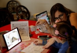 Isabel Martin del Campo, helps her daughter Ines, 6, on her English class, taught by the child's private school, as millions of students returned to classes virtually on Monday after schools were ordered into lockdown in March in Mexico City, Mexico.
