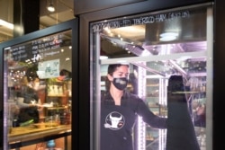 Vanesa Peredo, owner of A Taste of Spain, serves customers at Reading Terminal Market that has seen reduced foot traffic due to the coronavirus disease (COVID-19) outbreak in Philadelphia, Pennsylvania, U.S., February 20, 2021. (REUTERS/Hannah Beier)