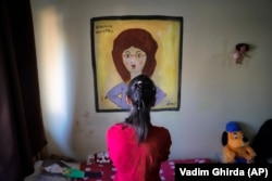 Elena, a girl living in a family style home with 10 other youths, poses for a photo in front of a painting of one of her teachers, in Bucharest, Romania, Wednesday, Nov. 1, 2017.