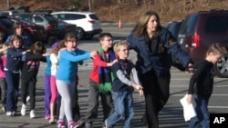 Connecticut State Police lead a line of children from the Sandy Hook Elementary School in Newtown, Conn. on Friday, Dec. 14, 2012 after a shooting at the school. (AP Photo/Newtown Bee, Shannon Hicks)