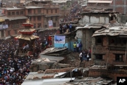 Nepalese devotees pull ropes tied to the chariot of Hindu god Bhairava as destroyed houses from last year's earthquake are seen during Bisket Jatra festival in Bhaktapur, Nepal, April 13, 2016.