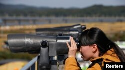 In this file photo, a Chinese tourist looks towards the north through a pair of binoculars at the Imjingak pavilion near the demilitarized zone which separates the two Koreas, in Paju, north of Seoul, Oct. 16, 2013.