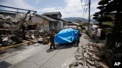 Les secouristes portent sur une civière une victime du séisme, âgée de 93 ans, à Mashiki, dans la préfecture de Kumamoto, dans le sud du Japon, 16 avril 2016