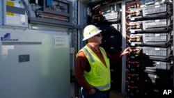 FILE - Mike Vandrely, construction manager, checks on a battery storage pod at Orsted's Eleven Mile Solar Center lithium-ion battery storage energy facility Thursday, Feb. 29, 2024, in Coolidge, Ariz. (AP Photo/Ross D. Franklin)