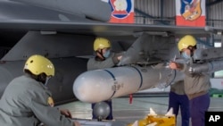 资料照：台湾嘉义一个空军基地的地勤人员在一架F-16战机的机翼上安装导弹。（2023年1月6日）