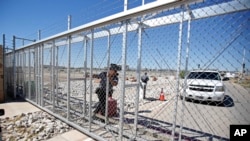 An agent with the Department of Homeland Security closes the exterior gate of the holding facility for immigrant children in Tornillo, Texas, near the Mexican border, Thursday, June 21, 2018.
