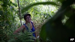 In this Jan. 6, 2020 photo, activist Ale Roque smiles as she sees a tree bearing fruit at her home in Rio's first favela, Morro da Providencia, Rio de Janeiro, Brazil. (AP Photo/Silvia Izquierdo)