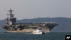 A Vietnamese passenger boat sails past U.S aircraft carrier USS Carl Vinson as it docks in Danang bay, Vietnam on Monday, March 5, 2018. (AP Photo/ Hau Dinh)