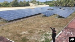A Taiwanese Coast Guard member points to solar panels on disputed island Itu Aba in the South China Sea.