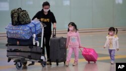 Passengers wear face masks after arriving at Hong Kong airport, Monday, March 23, 2020. Hong Kong will close its border to non-residents for 14 days starting from Wednesday, its chief executive announced on Monday after the number of coronavirus patients 