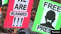 Des manifestants pour la liberté de la presse tiennent des pancartes devant le tribunal de première instance de Harare.
