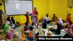 Yahya Edward Hendrawan dresses up as a clown to teach. His 5-year-old son Mirza, joins him. Here, they teach students at a boarding school in Tangerang, Indonesia, April 21, 2021. (REUTERS/Willy Kurniawan)