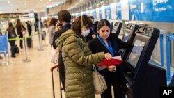 Une passagère portant un masque de protection obtient sa carte d'embarquement à l'aéroport international Adolfo Suarez-Barajas à la périphérie de Madrid, en Espagne, le mercredi 11 mars 2020. (AP Photo / Bernat Armangue)