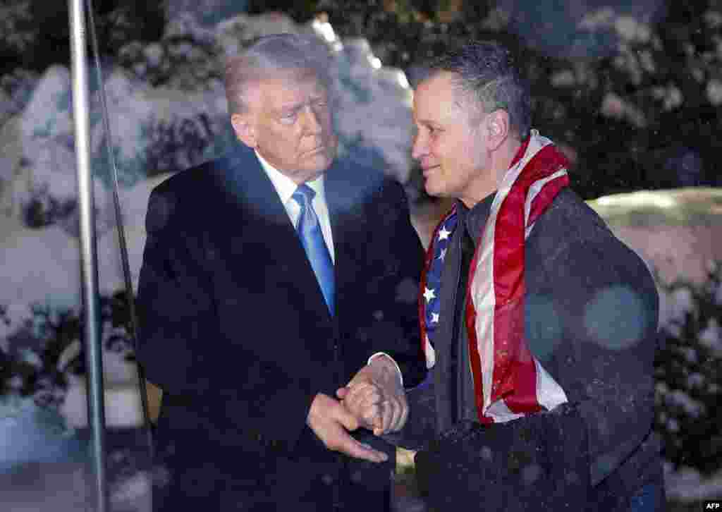 U.S. President Donald Trump greets just-released Marc Fogel, a U.S. teacher detained in Russia since 2021 on drugs charges, as he arrives at the White House under heavy snowfall in Washington on Feb. 11, 2025. (Photo by Ting Shen / AFP)