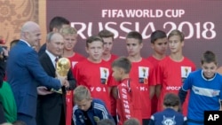 Le président russe Vladimir Poutine, deuxième à gauche, et le président de la Fifa Gianni Infantino, à gauche, portent le trophée de la Coupe du monde au stade Luzhniki, Moscou, Russie, 9 septembre 2017.