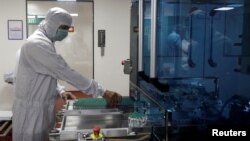 An employee removes vials of AstraZeneca's COVISHIELD, a COVID-19 vaccine, for inspection inside a lab at Serum Institute of India, in Pune, India, November 30, 2020. (REUTERS/Francis Mascarenhas)