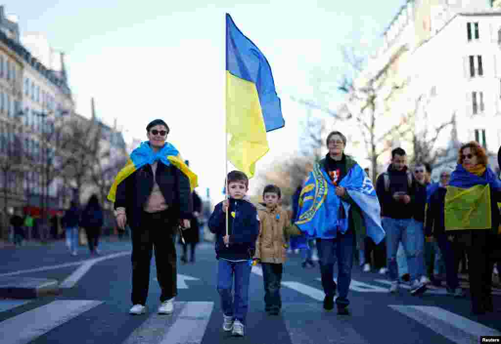 Париж, Франция Ребенок держит украинский флаг на акции протеста накануне третьей годовщины вторжения России в Украину, 23 февраля 2025 года