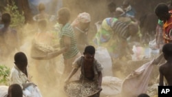 Femmes et enfants séparant la terre du grain renversé par un camion dont le conducteur a perdu le contrôle, dans la forêt de Machinga au Malawi, 24 mai 2016. (AP Photo/Tsvangirayi Mukwazhi)