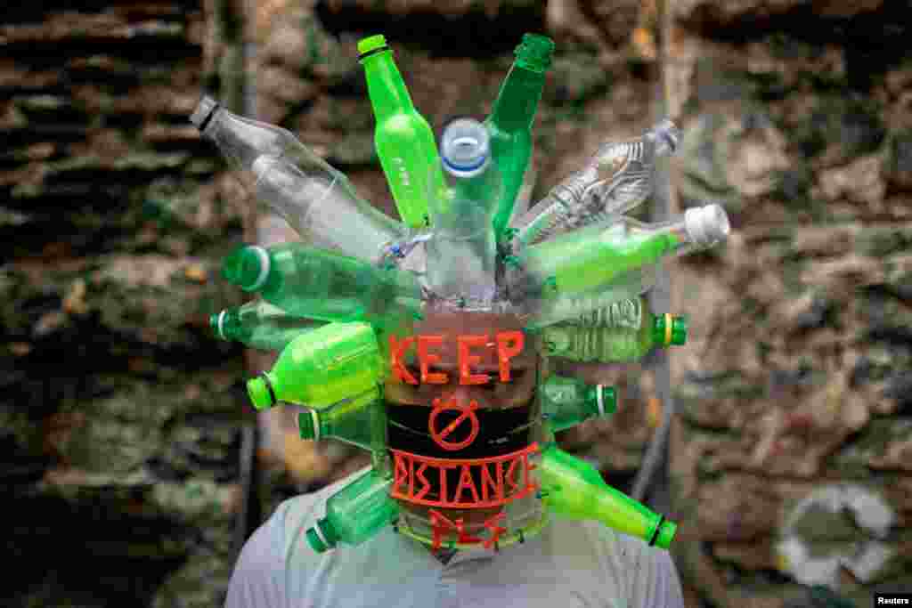 Filipino artist Leeroy New poses with a makeshift mask he designed with recycled materials as he adapts to the effects of the coronavirus pandemic in the art industry, in his studio in Quezon City, Metro Manila, Philippines.