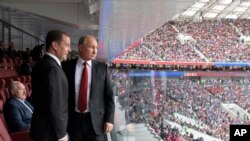 Russian President Vladimir Putin, right, and Russian Prime Minister Dmitry Medvedev look at the field during the match between Russia and Saudi Arabia which opens the 2018 soccer World Cup, at the Luzhniki stadium in Moscow, Russia.