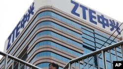 Un homme passe devant un bâtiment portant le logo ZTE à Pékin, le 6 mai 2018.